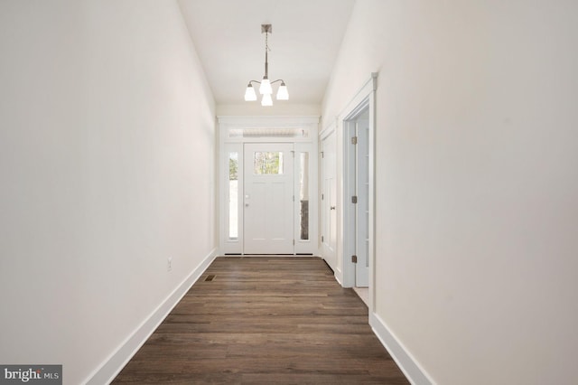 doorway featuring dark wood-type flooring and a notable chandelier