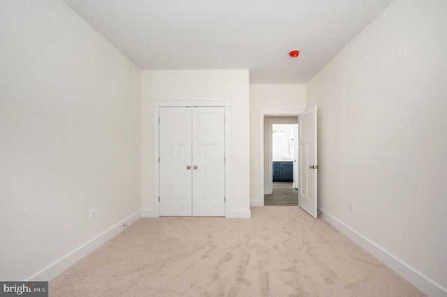 unfurnished bedroom with a closet and light colored carpet