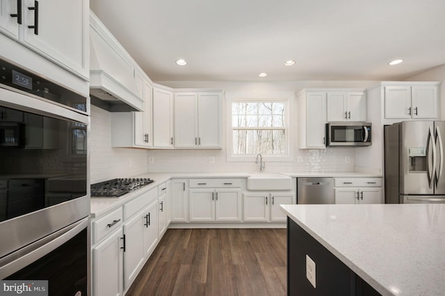 kitchen with sink, white cabinetry, stainless steel appliances, dark hardwood / wood-style flooring, and light stone counters