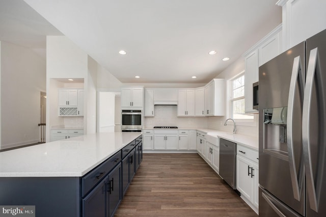 kitchen with white cabinetry, appliances with stainless steel finishes, blue cabinetry, a spacious island, and sink