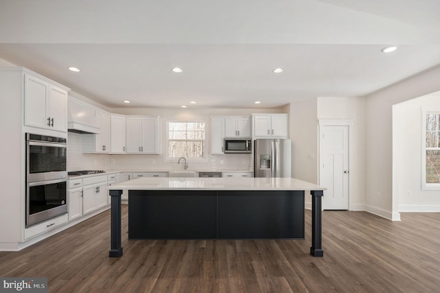 kitchen featuring a breakfast bar area, stainless steel appliances, white cabinetry, and a kitchen island