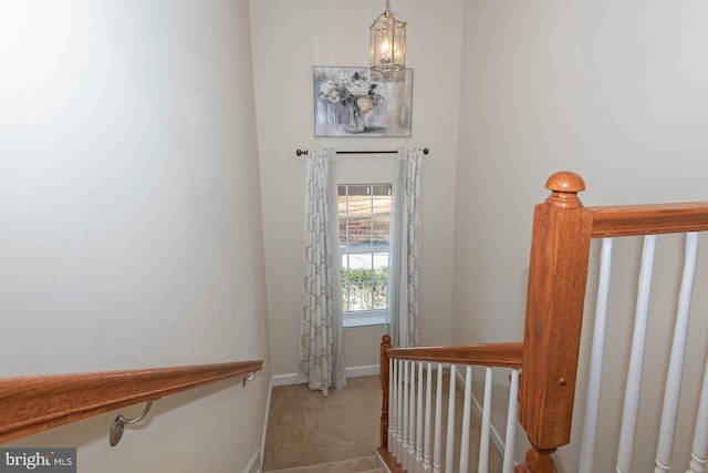 stairway with carpet floors and an inviting chandelier