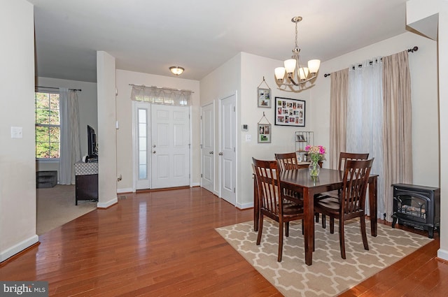 dining space with a wood stove, hardwood / wood-style flooring, and an inviting chandelier