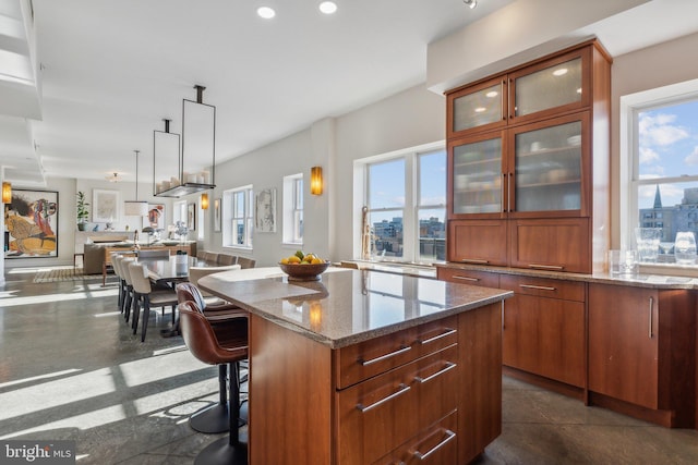 kitchen featuring a breakfast bar area, light stone countertops, a kitchen island, and decorative light fixtures