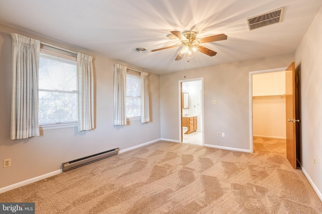 unfurnished bedroom with baseboard heating, ceiling fan, a spacious closet, connected bathroom, and a closet