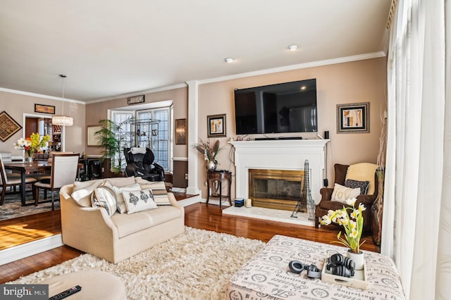 living room with wood-type flooring, ornamental molding, and a notable chandelier