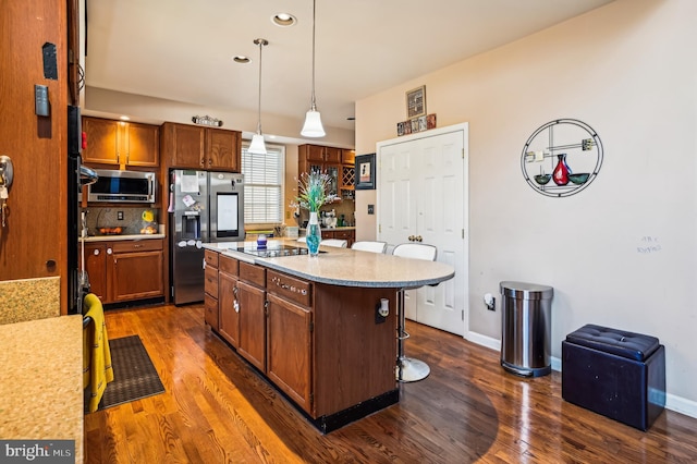 kitchen featuring a kitchen bar, appliances with stainless steel finishes, dark hardwood / wood-style flooring, and pendant lighting