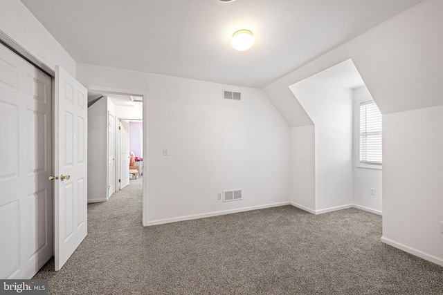 bonus room featuring vaulted ceiling and dark carpet