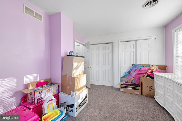 bedroom featuring light carpet and two closets