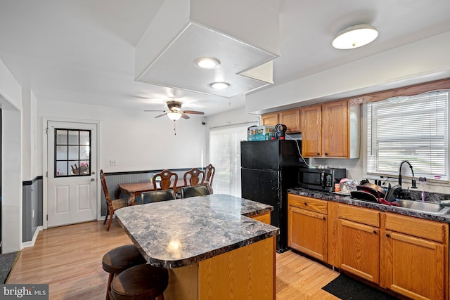 kitchen featuring a kitchen breakfast bar, black refrigerator, sink, light hardwood / wood-style floors, and a kitchen island