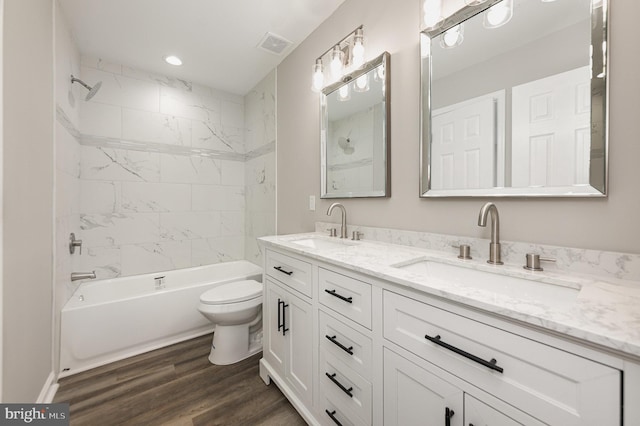 full bathroom with hardwood / wood-style floors, vanity, toilet, and tiled shower / bath