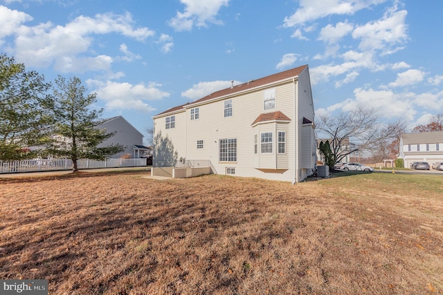 rear view of house featuring central AC unit and a lawn