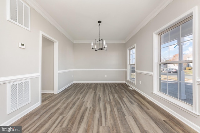 unfurnished dining area featuring crown molding, hardwood / wood-style floors, and an inviting chandelier