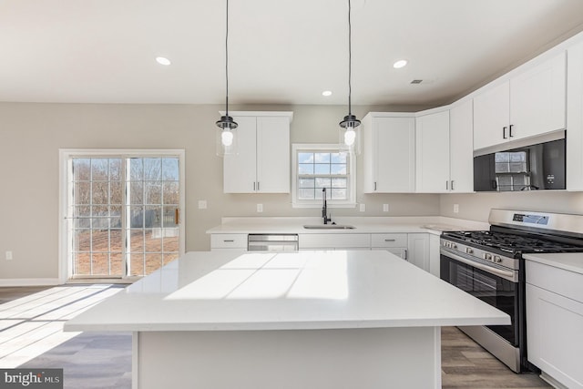 kitchen with appliances with stainless steel finishes, white cabinetry, hanging light fixtures, and sink