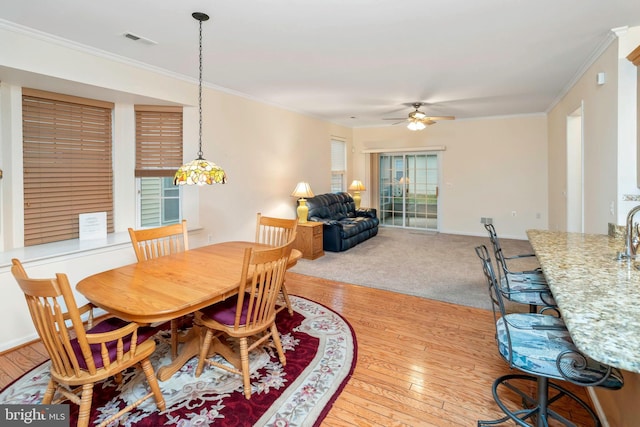 dining space with ceiling fan, a healthy amount of sunlight, crown molding, and light hardwood / wood-style flooring