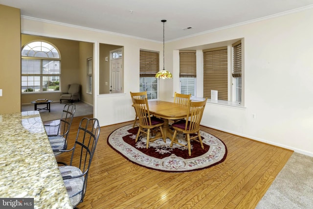 dining space featuring wood-type flooring and crown molding