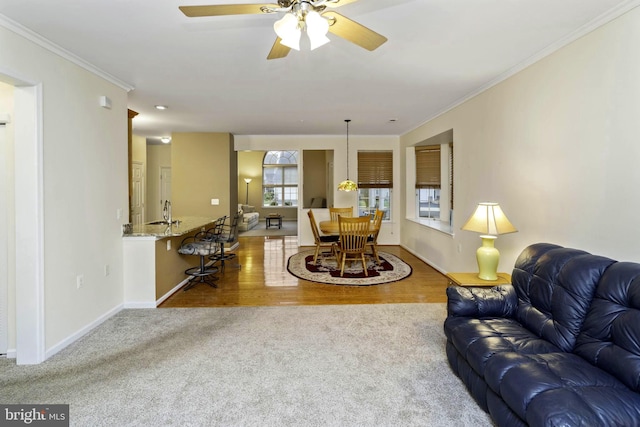 living room with ceiling fan, light hardwood / wood-style floors, ornamental molding, and sink