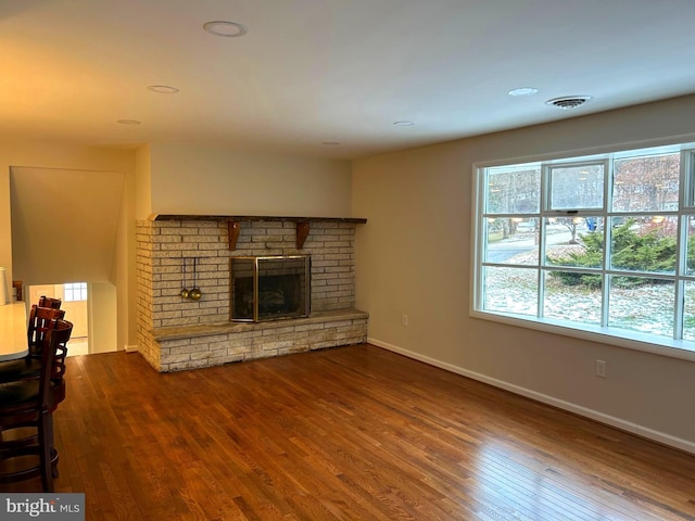 unfurnished living room with hardwood / wood-style floors and a brick fireplace