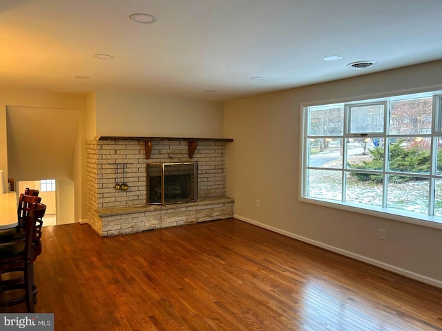 unfurnished living room featuring hardwood / wood-style floors and a brick fireplace