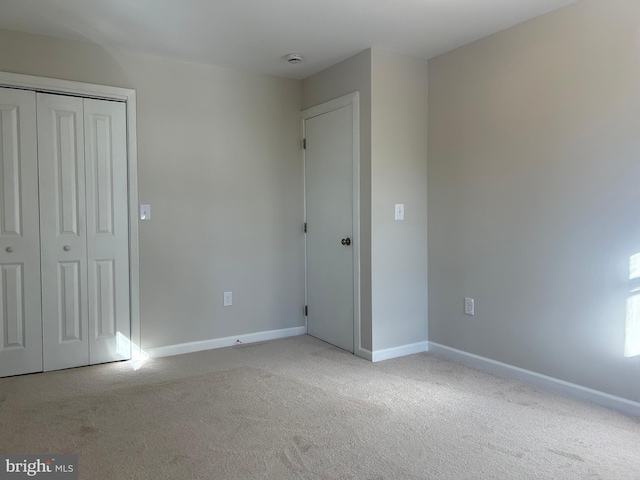 unfurnished bedroom with light carpet and a closet