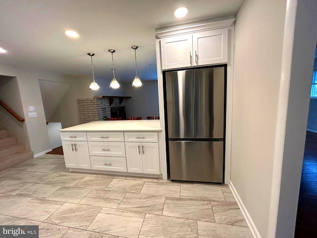 kitchen with stainless steel fridge, white cabinets, and decorative light fixtures