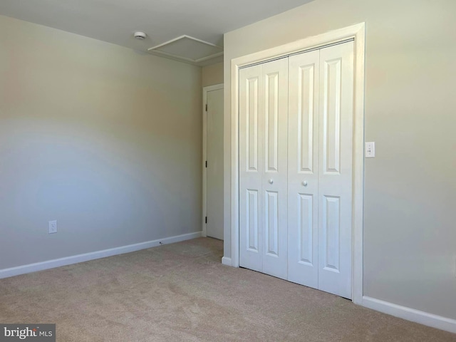 unfurnished bedroom with light colored carpet and a closet