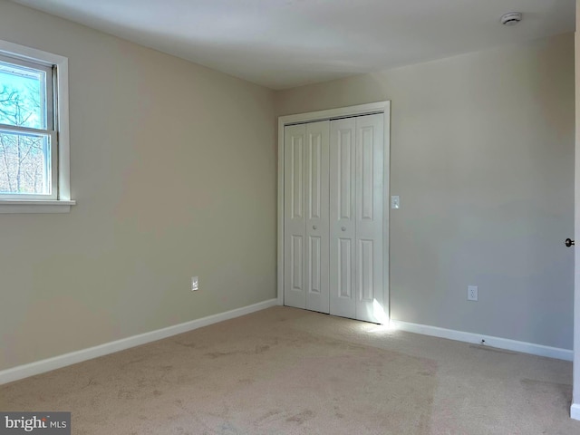 unfurnished bedroom featuring light colored carpet and a closet