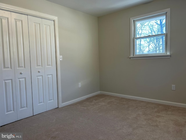 unfurnished bedroom featuring light carpet and a closet