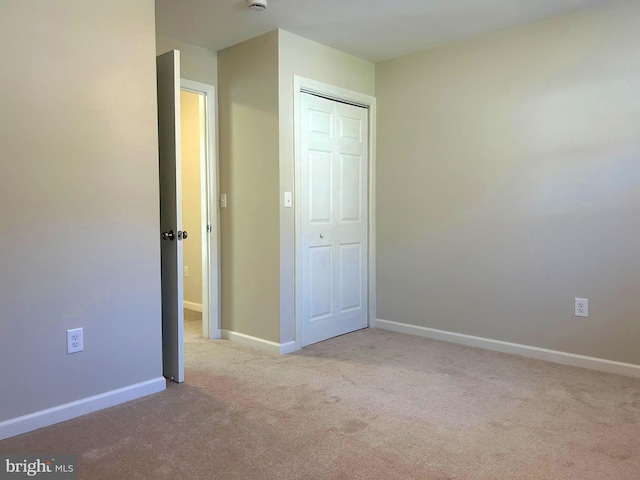 unfurnished bedroom featuring a closet and light colored carpet