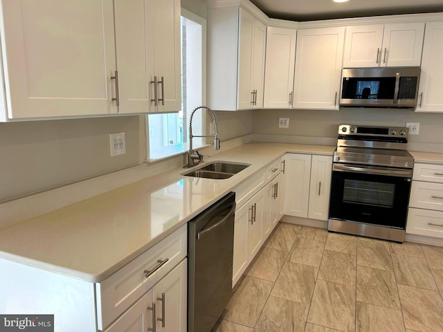 kitchen with light stone counters, white cabinetry, sink, and appliances with stainless steel finishes