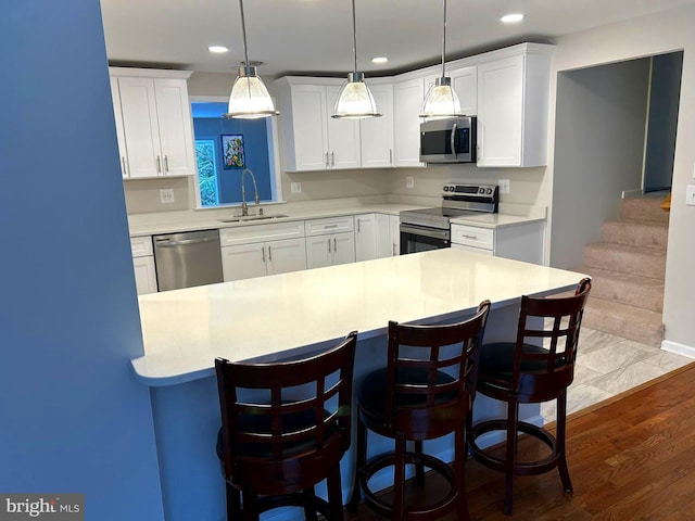 kitchen featuring wood-type flooring, stainless steel appliances, white cabinetry, and sink