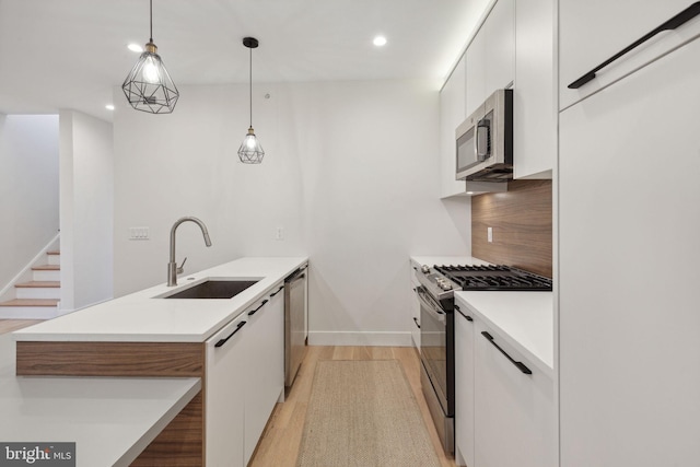 kitchen featuring sink, backsplash, decorative light fixtures, white cabinets, and appliances with stainless steel finishes