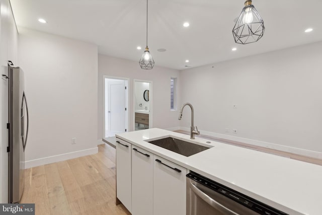 kitchen with stainless steel appliances, sink, white cabinets, light hardwood / wood-style floors, and hanging light fixtures