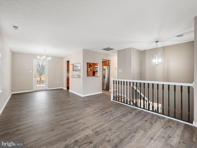 spare room with dark hardwood / wood-style flooring and an inviting chandelier