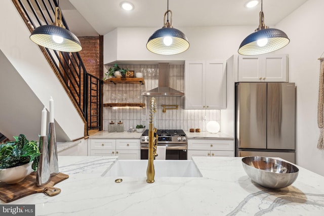 kitchen featuring light stone countertops, stainless steel appliances, white cabinetry, and wall chimney exhaust hood