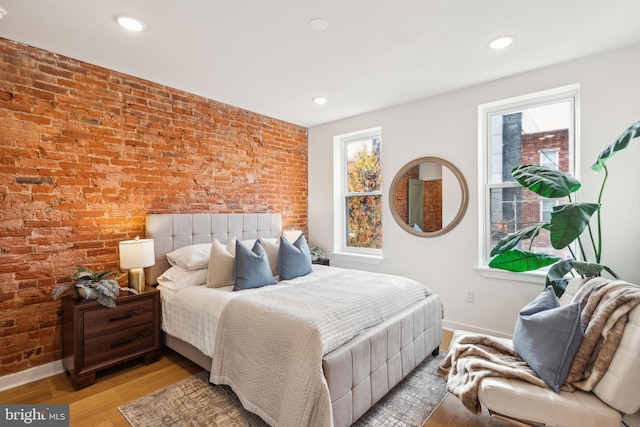 bedroom with light hardwood / wood-style flooring and brick wall