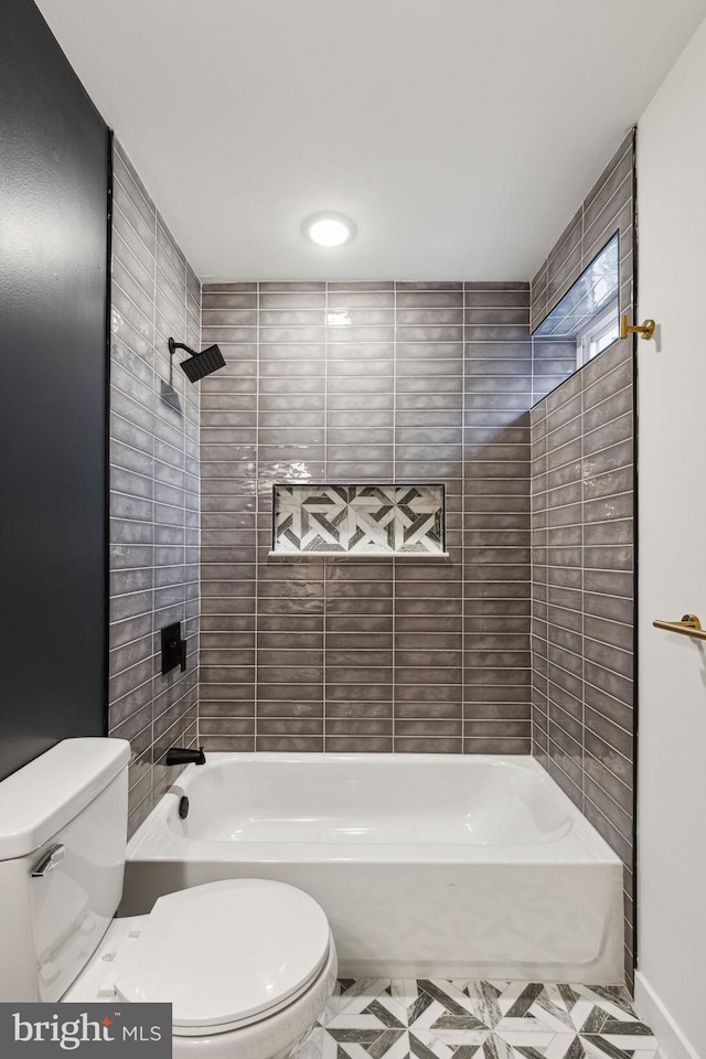 bathroom featuring tiled shower / bath combo and toilet