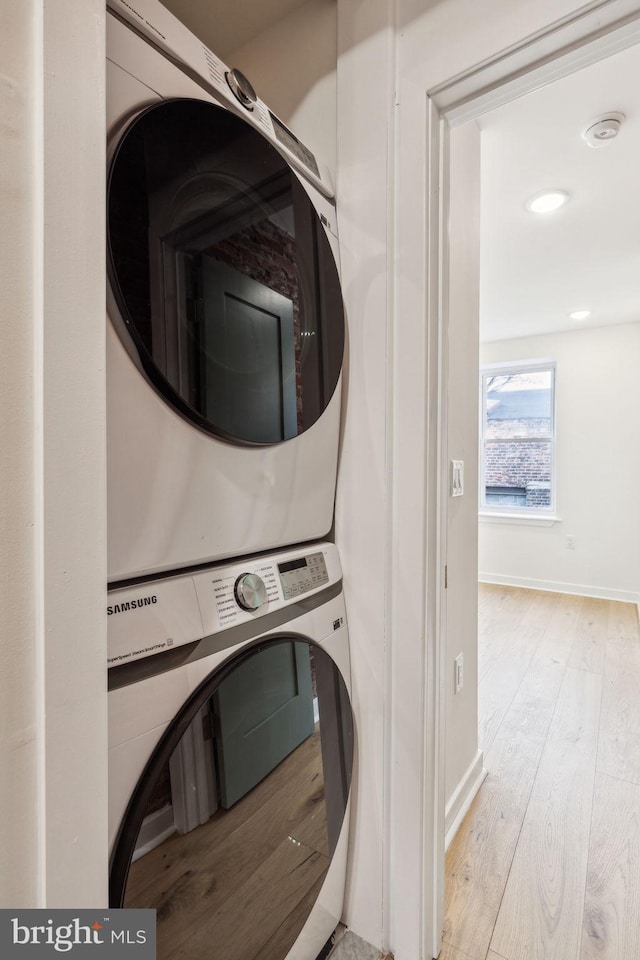 washroom featuring light hardwood / wood-style flooring and stacked washer and clothes dryer