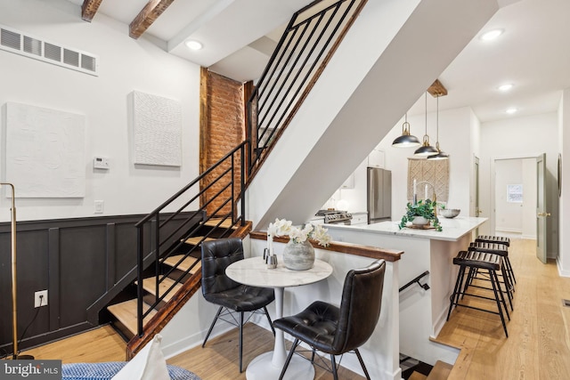 dining room with beam ceiling and light hardwood / wood-style floors