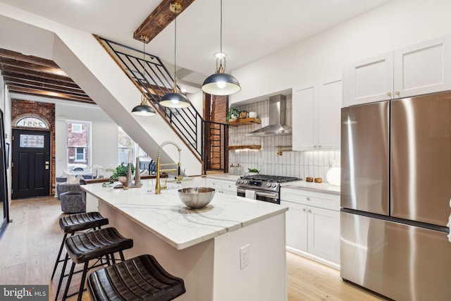 kitchen with white cabinets, appliances with stainless steel finishes, light hardwood / wood-style floors, and wall chimney range hood