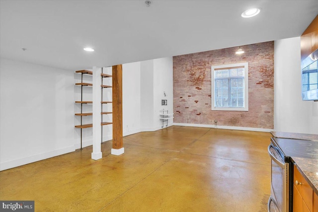 interior space featuring plenty of natural light, brick wall, finished concrete floors, and baseboards