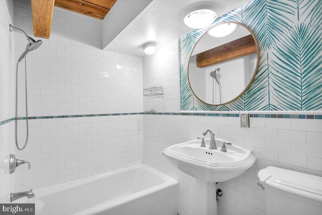 full bathroom featuring bathing tub / shower combination, toilet, and tile walls