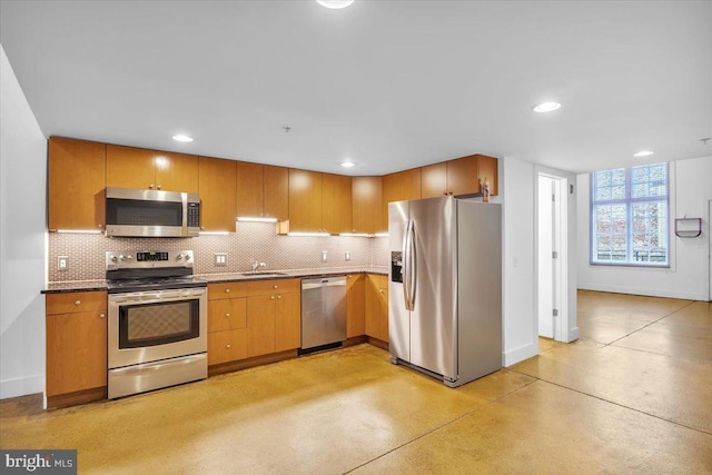 kitchen featuring concrete flooring, appliances with stainless steel finishes, baseboards, and decorative backsplash