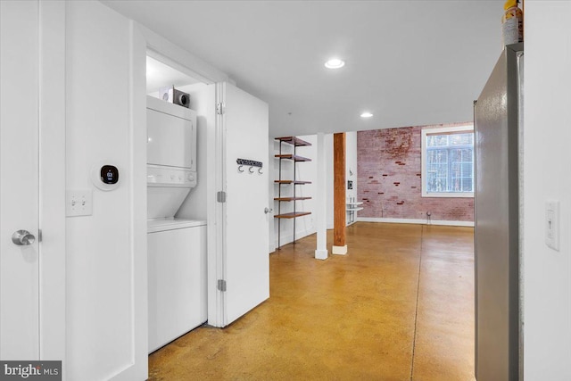 hallway featuring recessed lighting, finished concrete floors, stacked washing maching and dryer, baseboards, and stairs