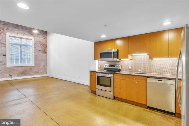 kitchen with baseboards, decorative backsplash, appliances with stainless steel finishes, finished concrete floors, and a sink