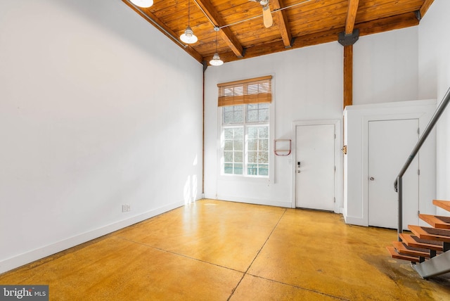 foyer entrance with finished concrete floors, wood ceiling, stairway, and baseboards