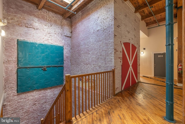 corridor with wood ceiling, beamed ceiling, a high ceiling, and wood finished floors