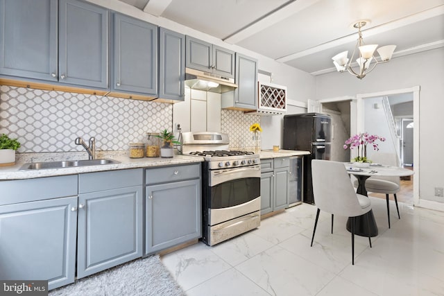 kitchen featuring backsplash, black refrigerator, sink, hanging light fixtures, and stainless steel range with gas stovetop