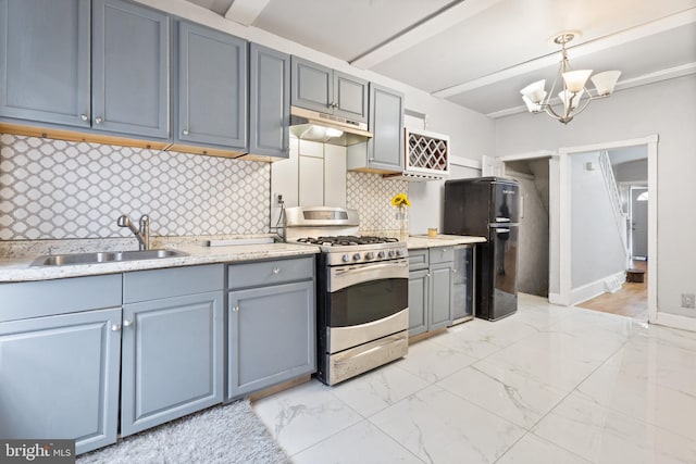 kitchen with black refrigerator, sink, stainless steel gas range, tasteful backsplash, and decorative light fixtures