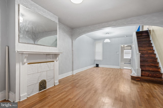 unfurnished living room with an inviting chandelier and light wood-type flooring